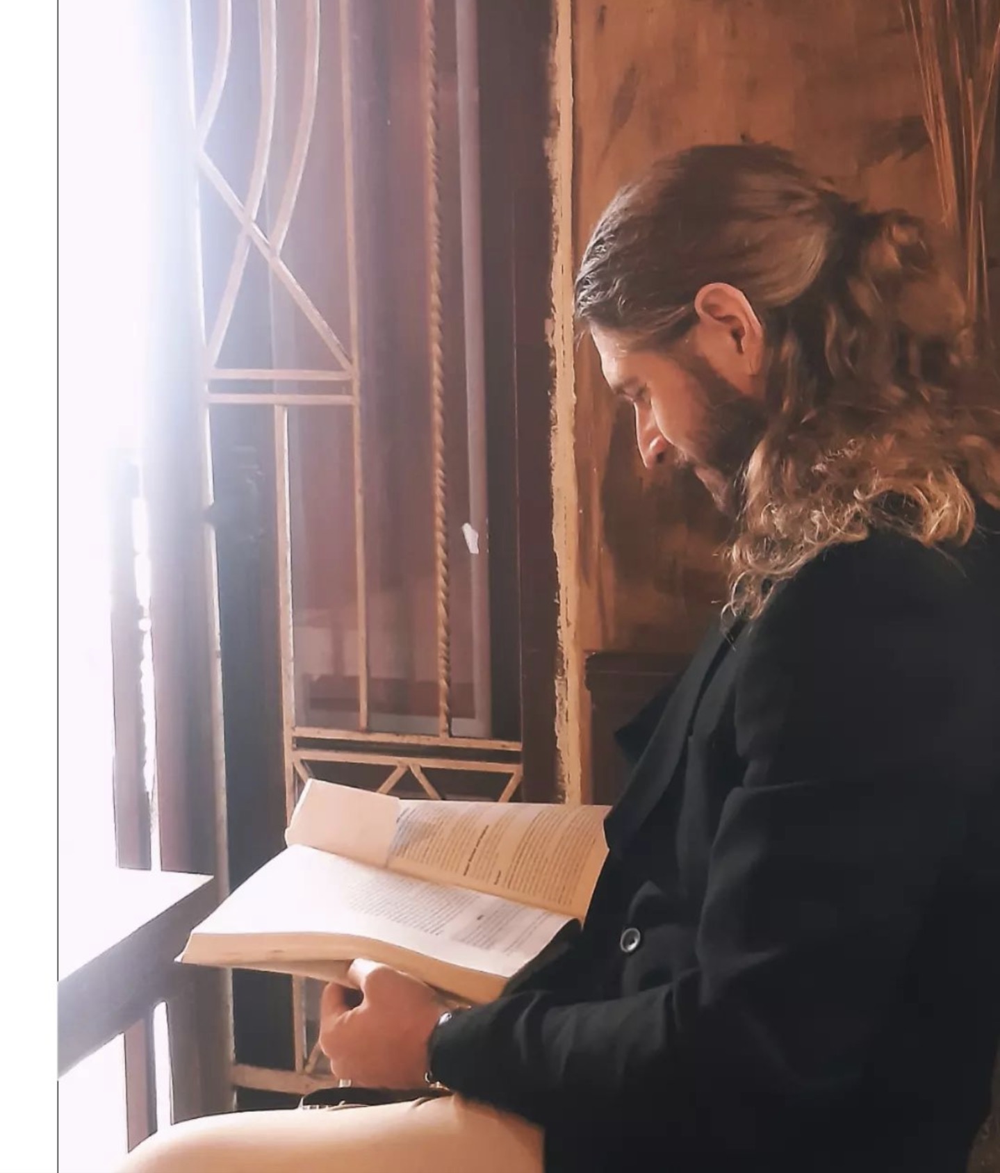 Dr. Julian reading by a window with natural light