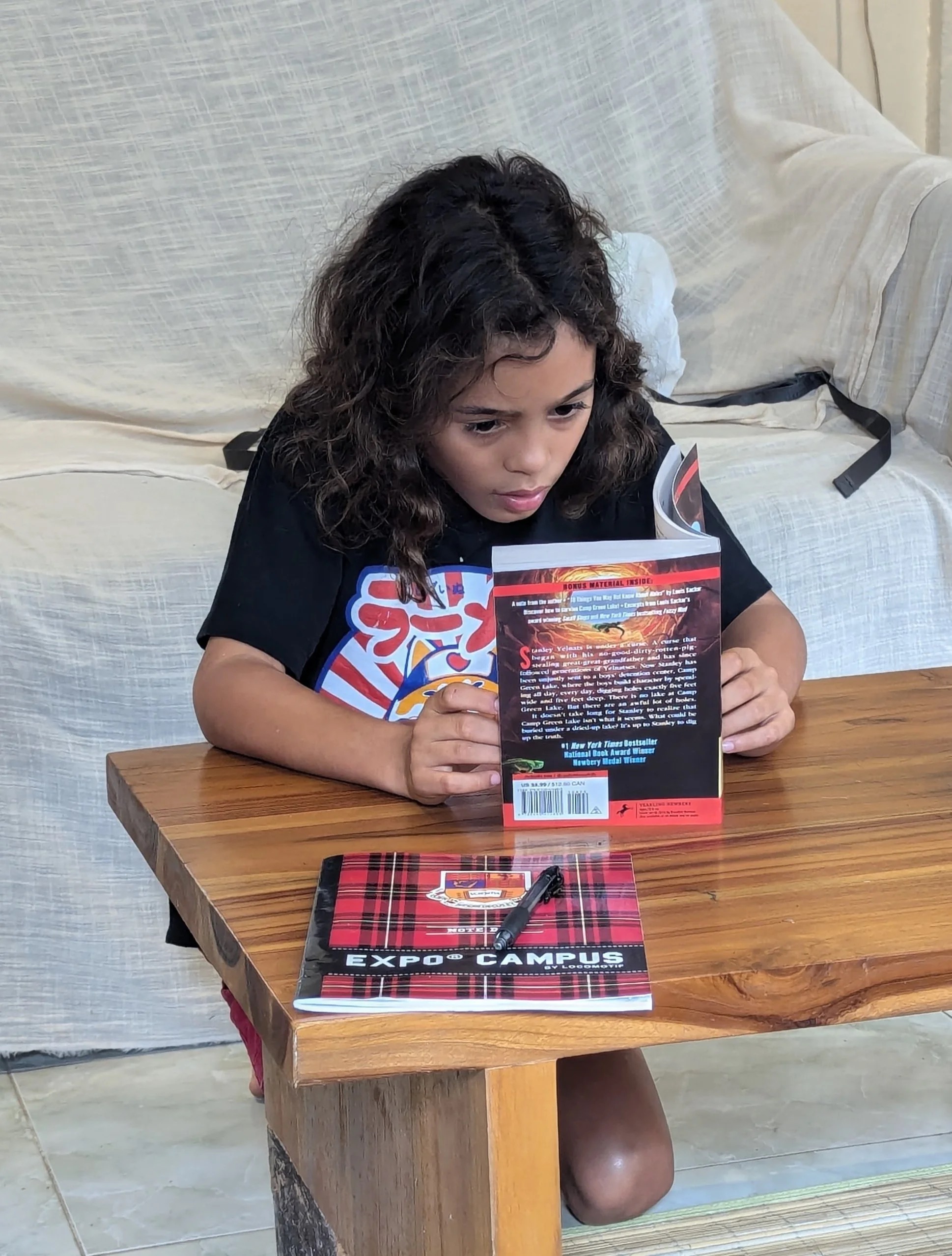 A young student absorbed in reading Holes by Louis Sachar